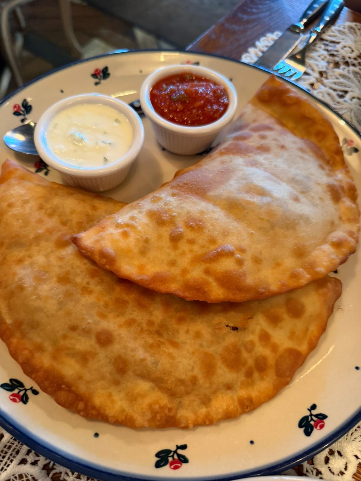 Chebureki on a floral plate with two dipping sauces
