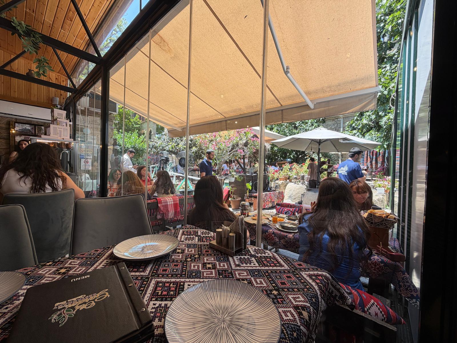 Glassed garden conservatory dining room with kilim-covered tables at Old Garden, Icherisheher, Baku
Old Garden, Icherisheher — glass on one side, courtyard on the other.