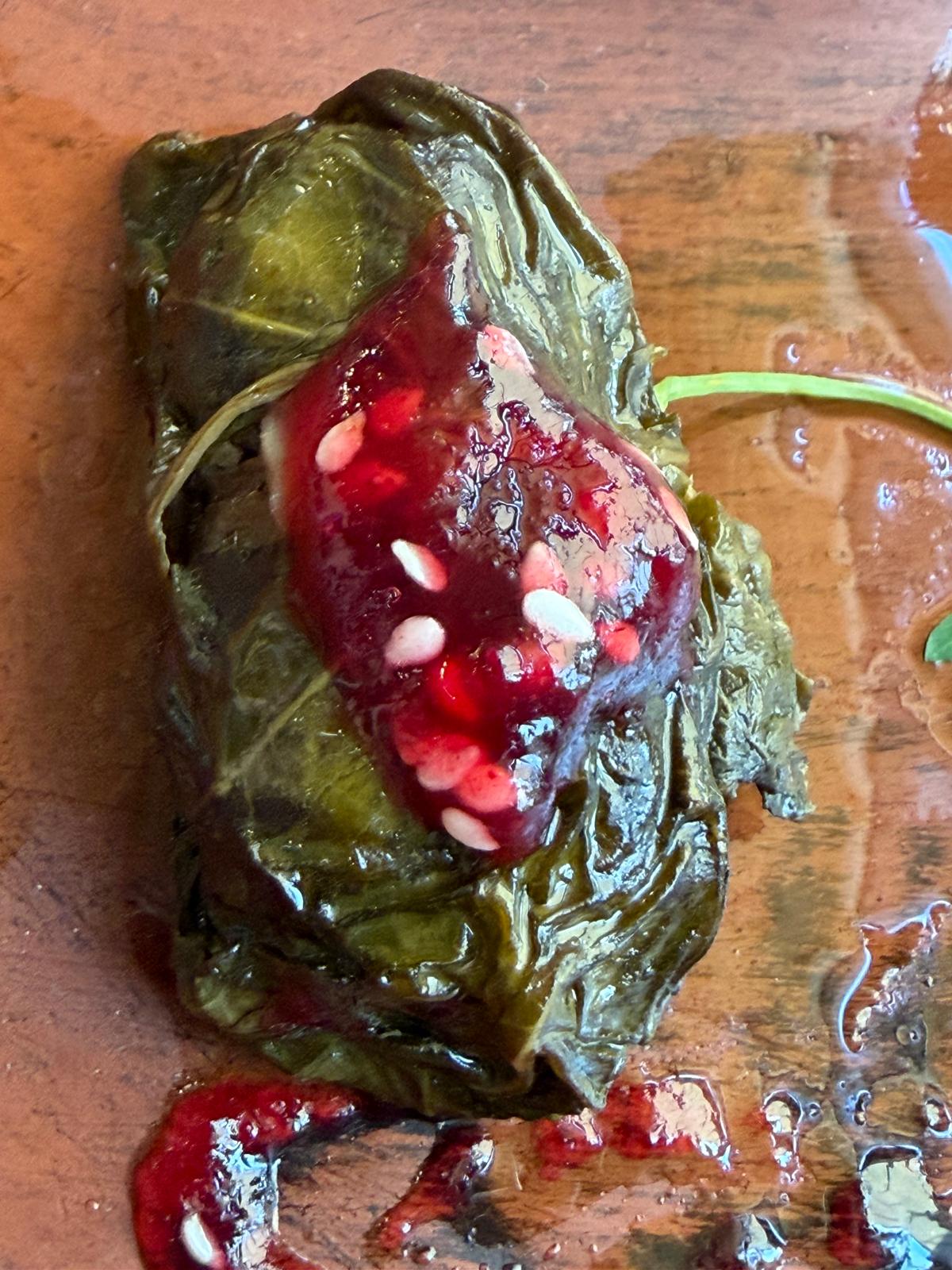 Close-up of a dolma topped with tart cornelian cherry sauce and sesame seeds.
Cornelian cherry, zoğal — sesame on top, sour where the yogurt is sharp.