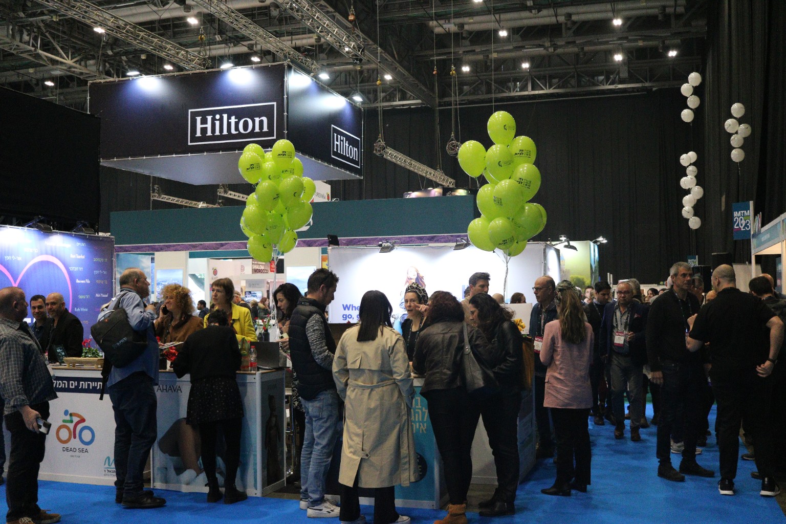Visitors networking at a tourism trade exhibition beneath a Hilton sign
