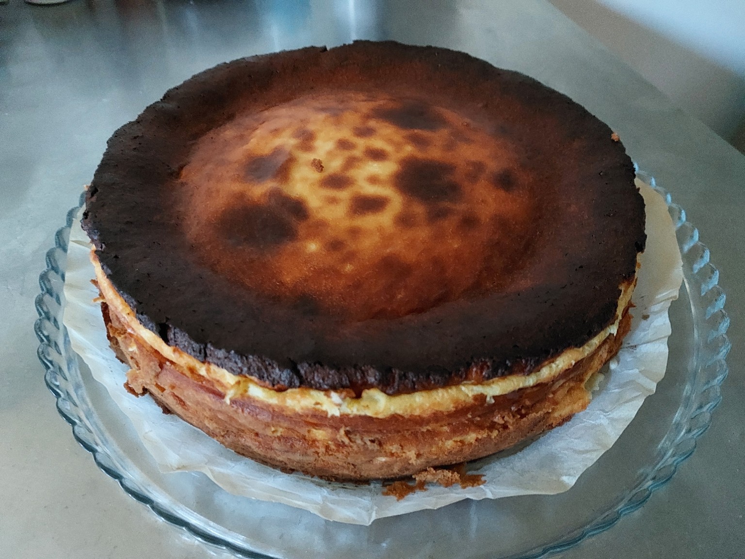 Homemade Basque cheesecake with a deeply browned top on a glass serving plate
