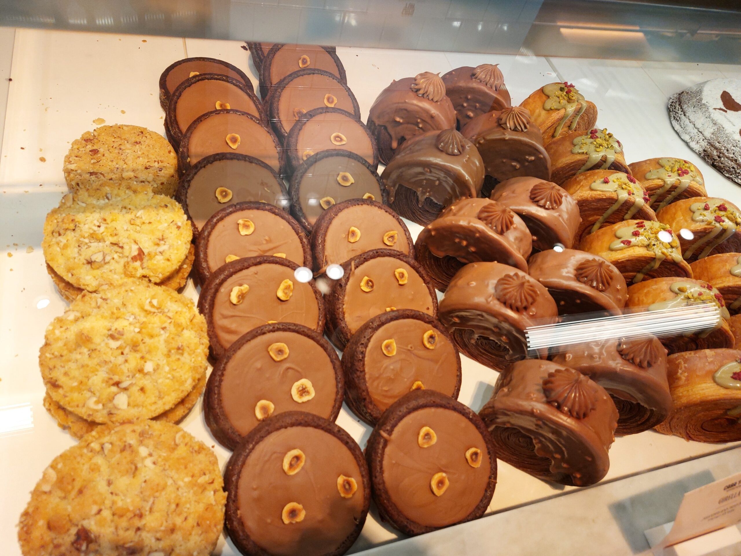 Chocolate tarts topped with hazelnuts, nut cookies, chocolate-glazed girella rolls and pistachio-drizzled pastries in the Casa Tua case
