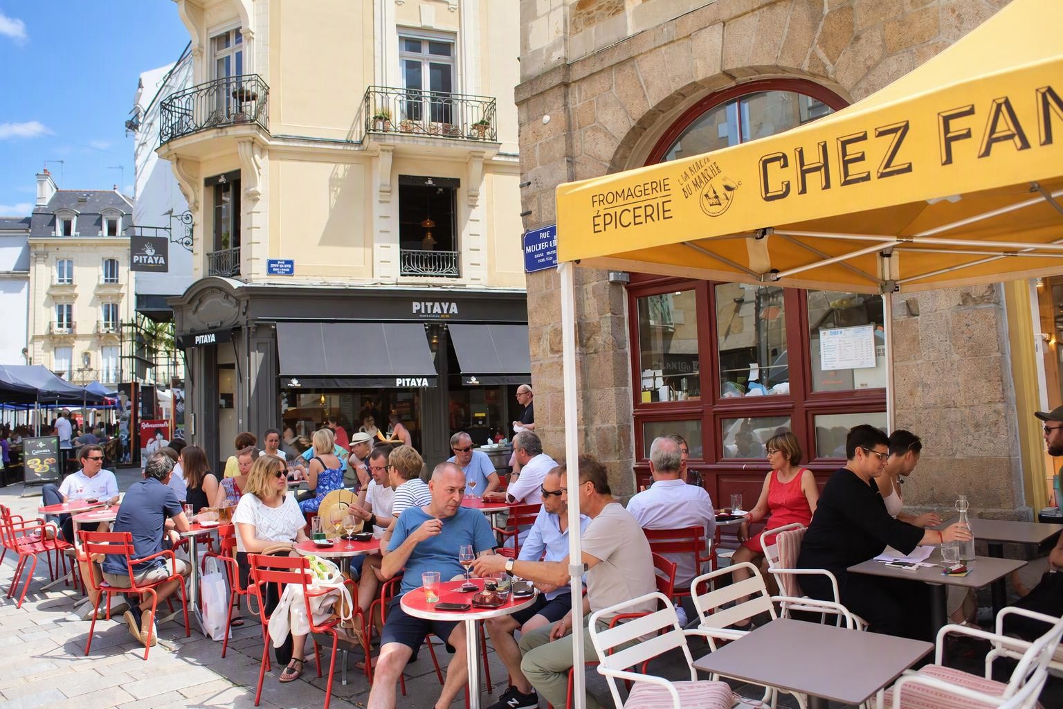 Outdoor dining on Rue Rallier du Baty in Rennes, with red café chairs, a yellow Chez Fanch awning and pale buildings with wrought-iron balconies.