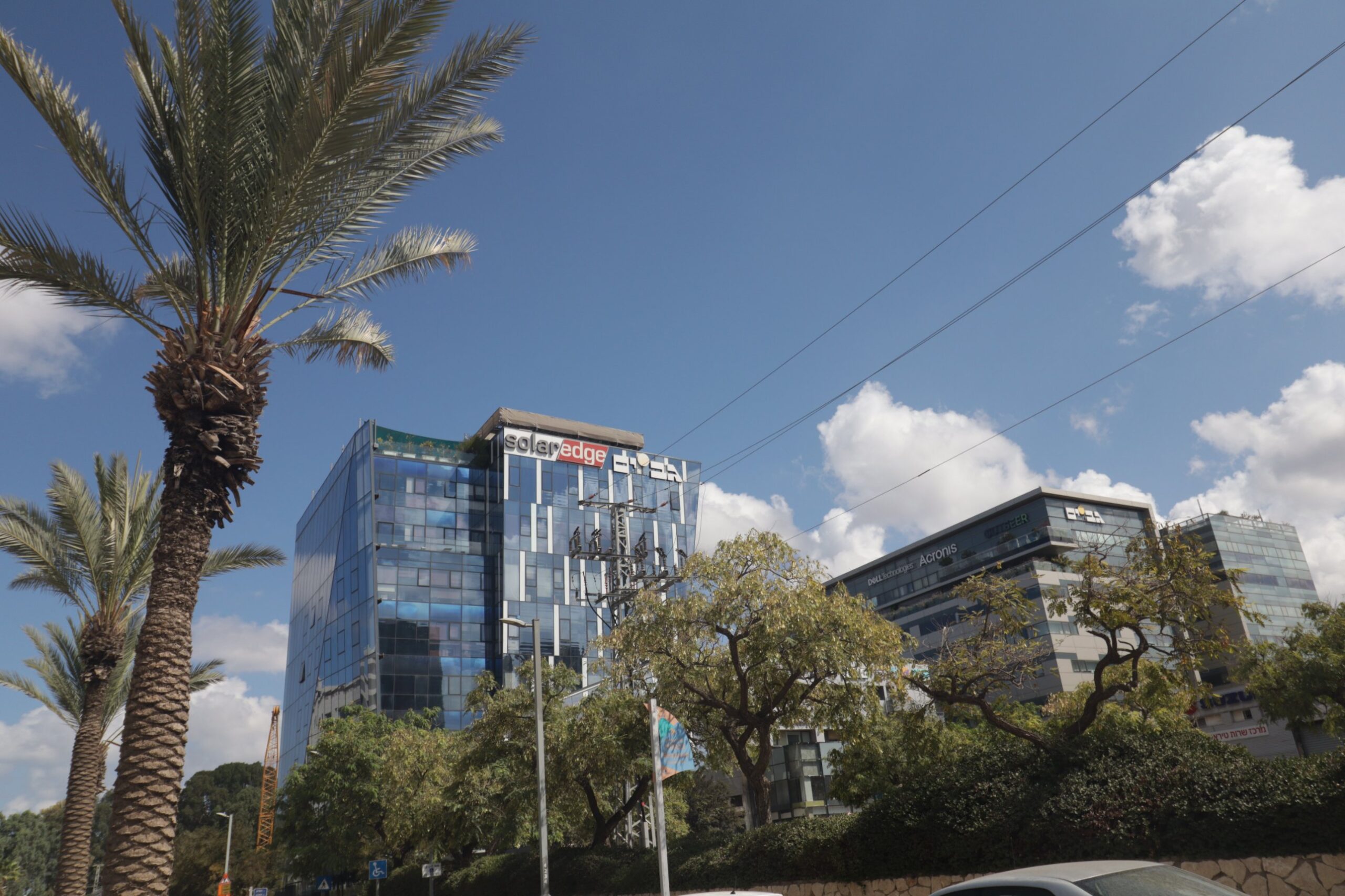 SolarEdge headquarters glass tower in Herzliya Pituach, with an office building carrying Dell Technologies and Acronis signs
